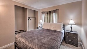 A bedroom with a bed, nightstands, a lamp, and a door. - 3 Mi to Lake Powell: Page Home w/ Patio & BBQ (Page)