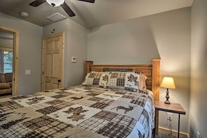 Een slaapkamer met een groot bed, een houten hoofdeinde, een nachtkastje met een lamp en een plafondventilator.