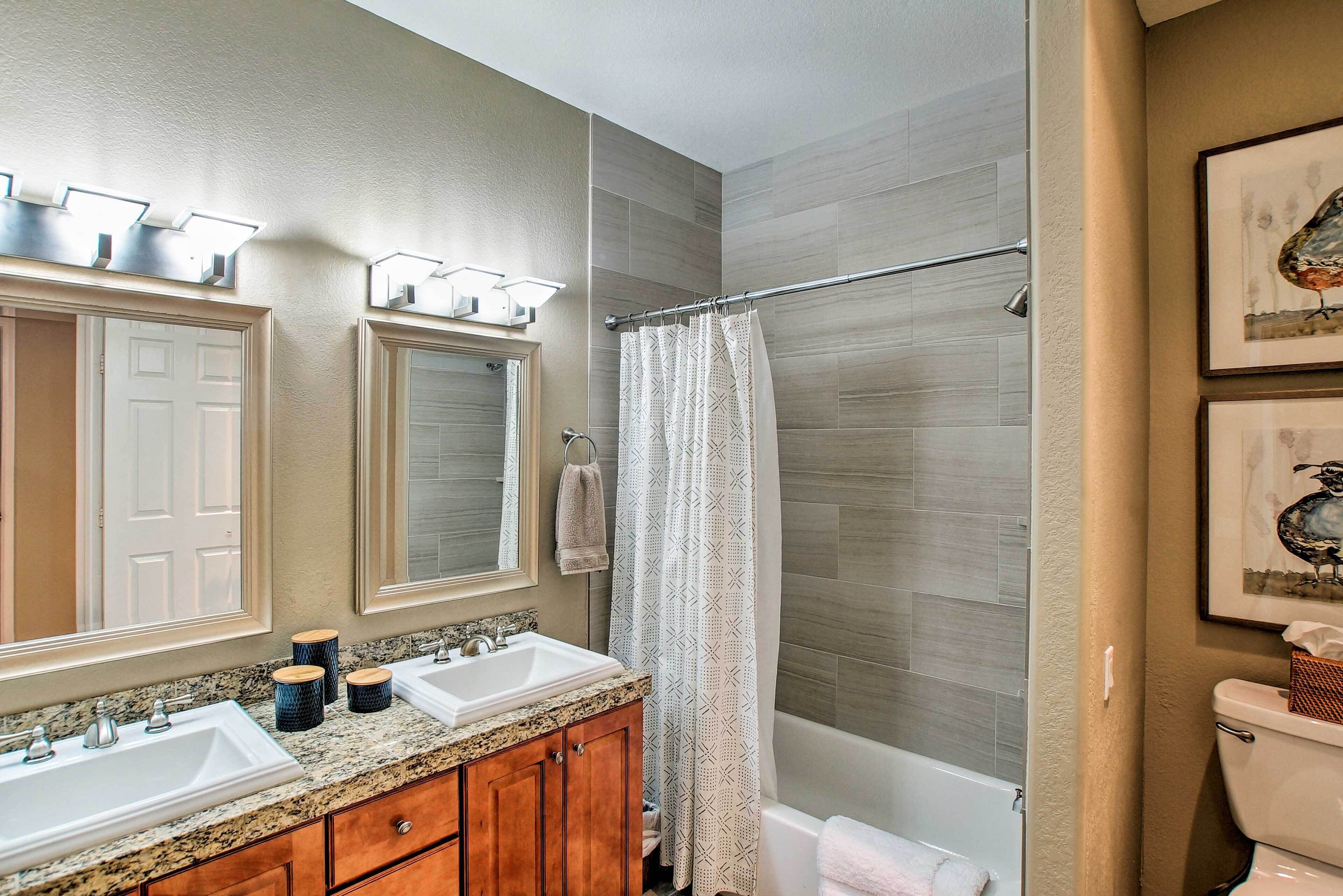 A bathroom with two sinks, a mirror, a shower curtain, and a toilet.