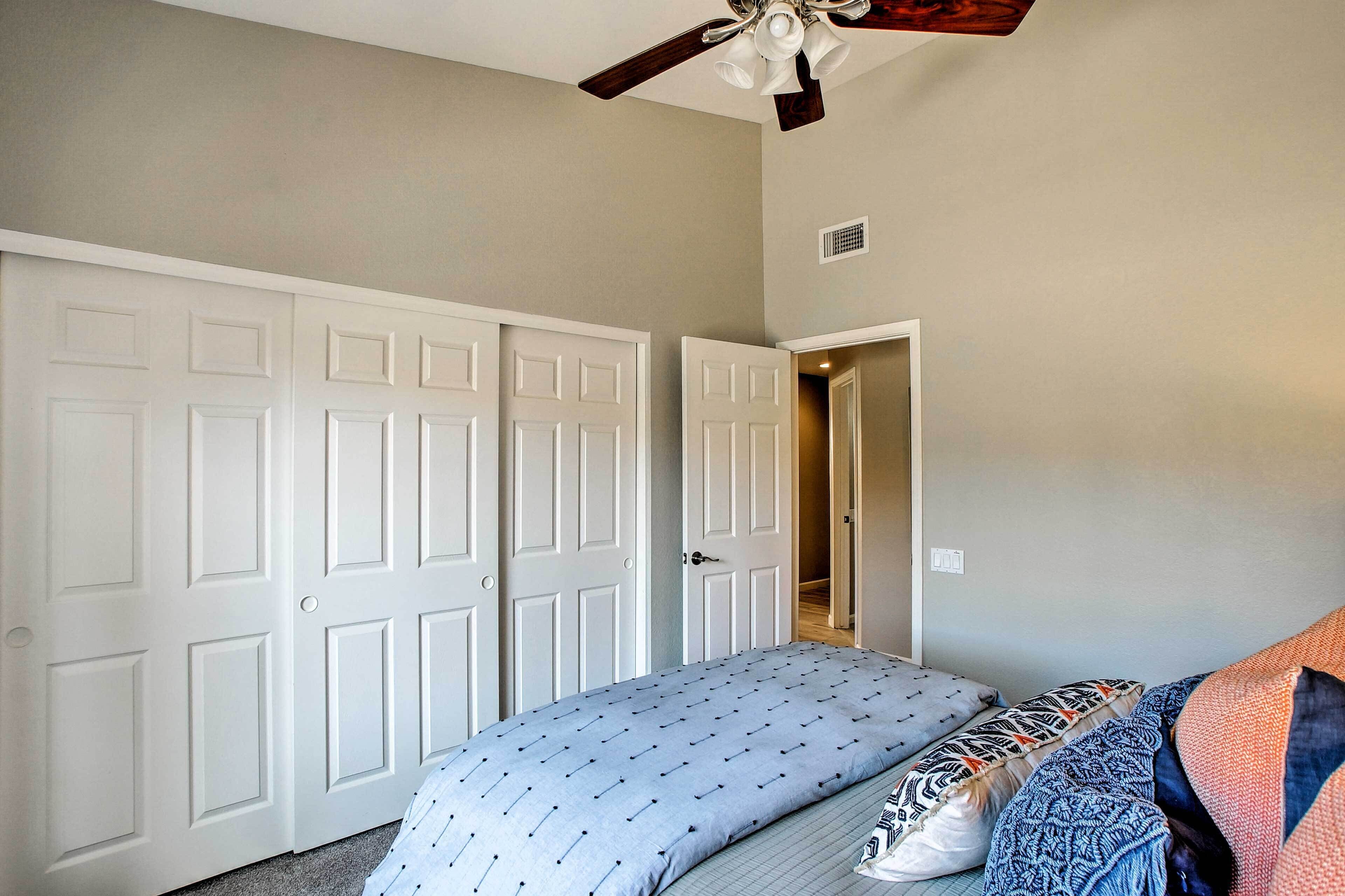 A bedroom with a bed, a ceiling fan, and a door leading to another room.