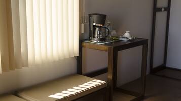 A small, modern room with a wooden bench, a coffee maker, and a table.