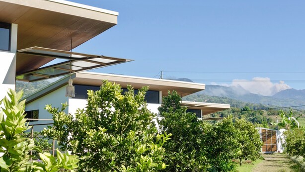 Une maison moderne avec un toit plat, de grandes fenêtres et une vue sur les montagnes.