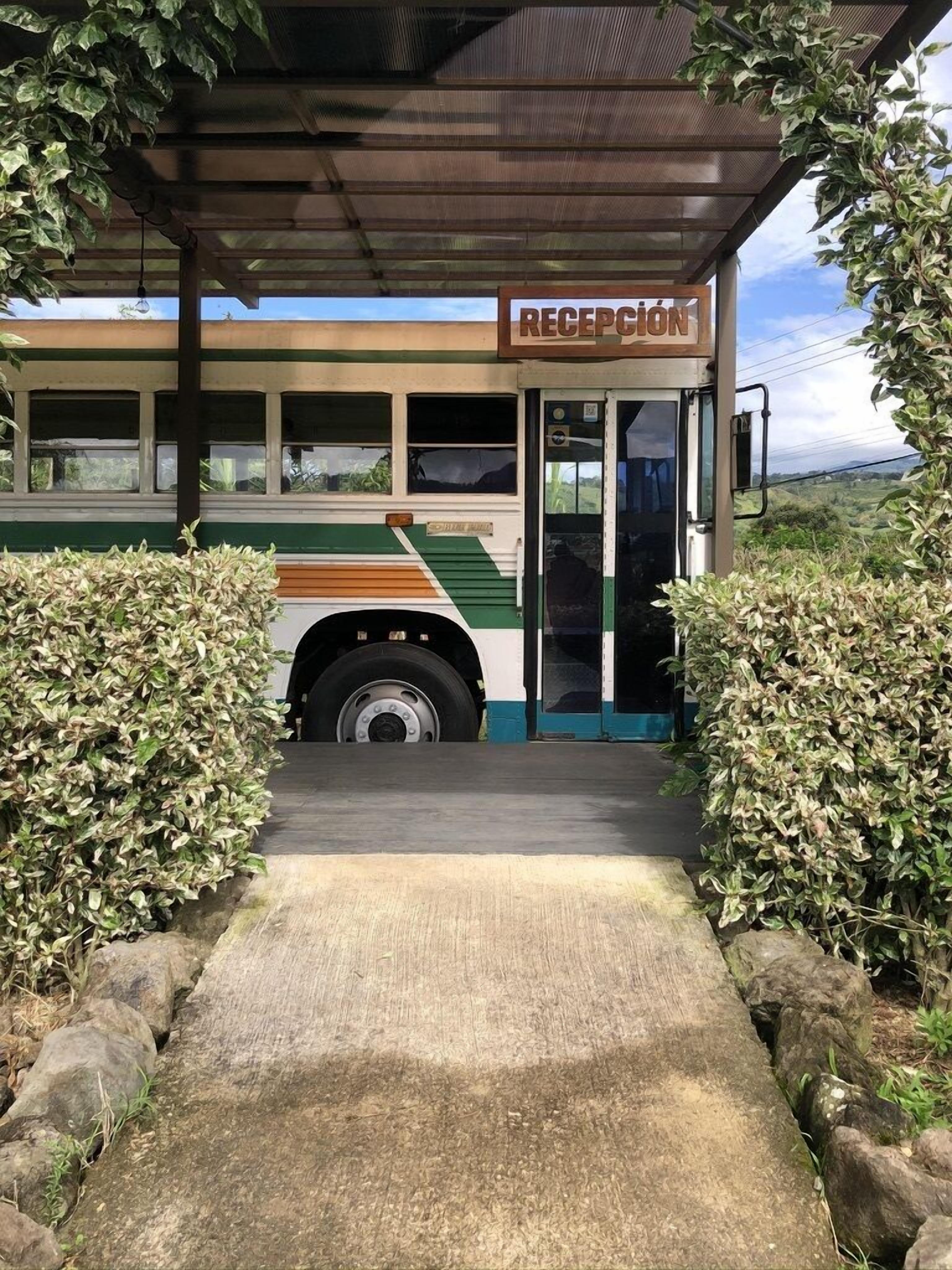 Un autobus doté d’un espace d’accueil, entouré de verdure et agrémenté d’une allée couverte.