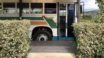 Un autobus doté d’un espace d’accueil, entouré de verdure et agrémenté d’une allée couverte.