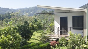 Une maison moderne dotée d’un balcon donnant sur un jardin luxuriant et sur des collines lointaines.