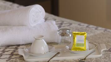 A neatly made bed with a tray containing a white cup, a small glass container, and a yellow packet, likely containing a snack or toiletry item.