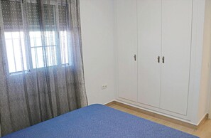 A room with a bed, a wardrobe, and a window with curtains.