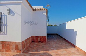 A rooftop terrace with a tiled floor, white walls, and a tiled roof.