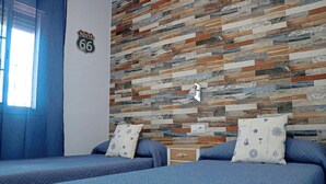 Een kamer met twee bedden, een Route 66 bord, een houten wand en een raam met blauwe gordijnen.