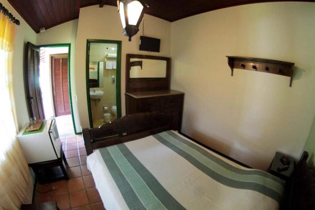 Ein Schlafzimmer mit Bett, Schreibtisch, Spiegel und Regal.