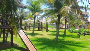 A playground with a slide, climbing structures, and palm trees. - OYO Pousada do Wagner, Rio das Ostras (Rio das Ostras)