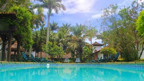 A swimming pool surrounded by palm trees and lounge chairs. - OYO Pousada do Wagner, Rio das Ostras (Rio das Ostras)