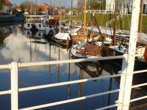 A marina with various boats docked, a white railing in the foreground, and buildings in the background.
