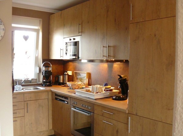 A kitchen with wooden cabinets, a built-in oven, a coffee maker, and a sink.