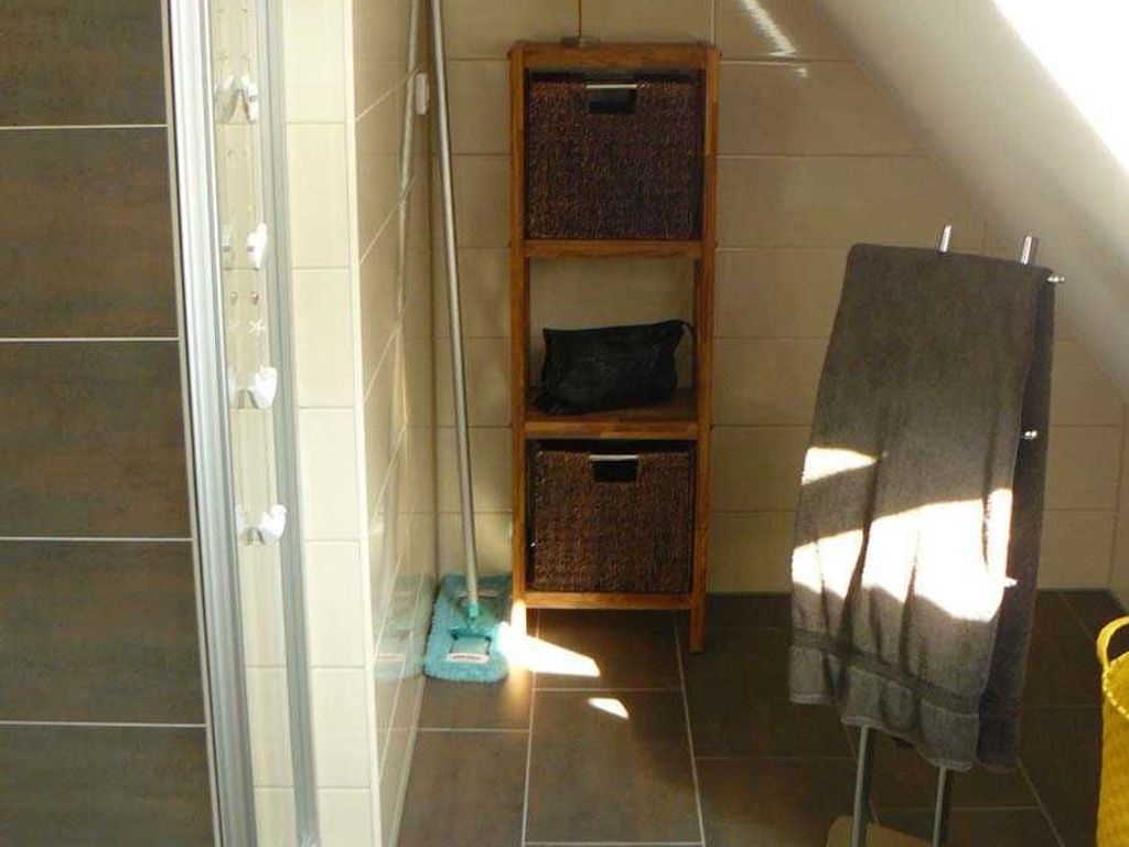 Un baño con ducha, un perchero y una estantería con cestas.
