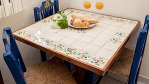 A dining table with a floral tile pattern, two blue chairs, a plate with croissants, and two glasses of orange juice. - SIMI-HA-2BR-TULUM... (TULUM)