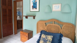 A bedroom with a wicker headboard, a wooden dresser, a water dispenser, and a framed poster on the wall. - SIMI-HA-2BR-TULUM... (TULUM)