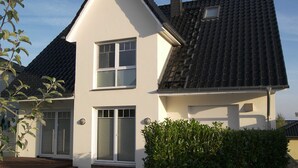 Ein zweistöckiges Haus mit Satteldach, einer Garage und einem gepflegten Vorgarten mit Hecken.