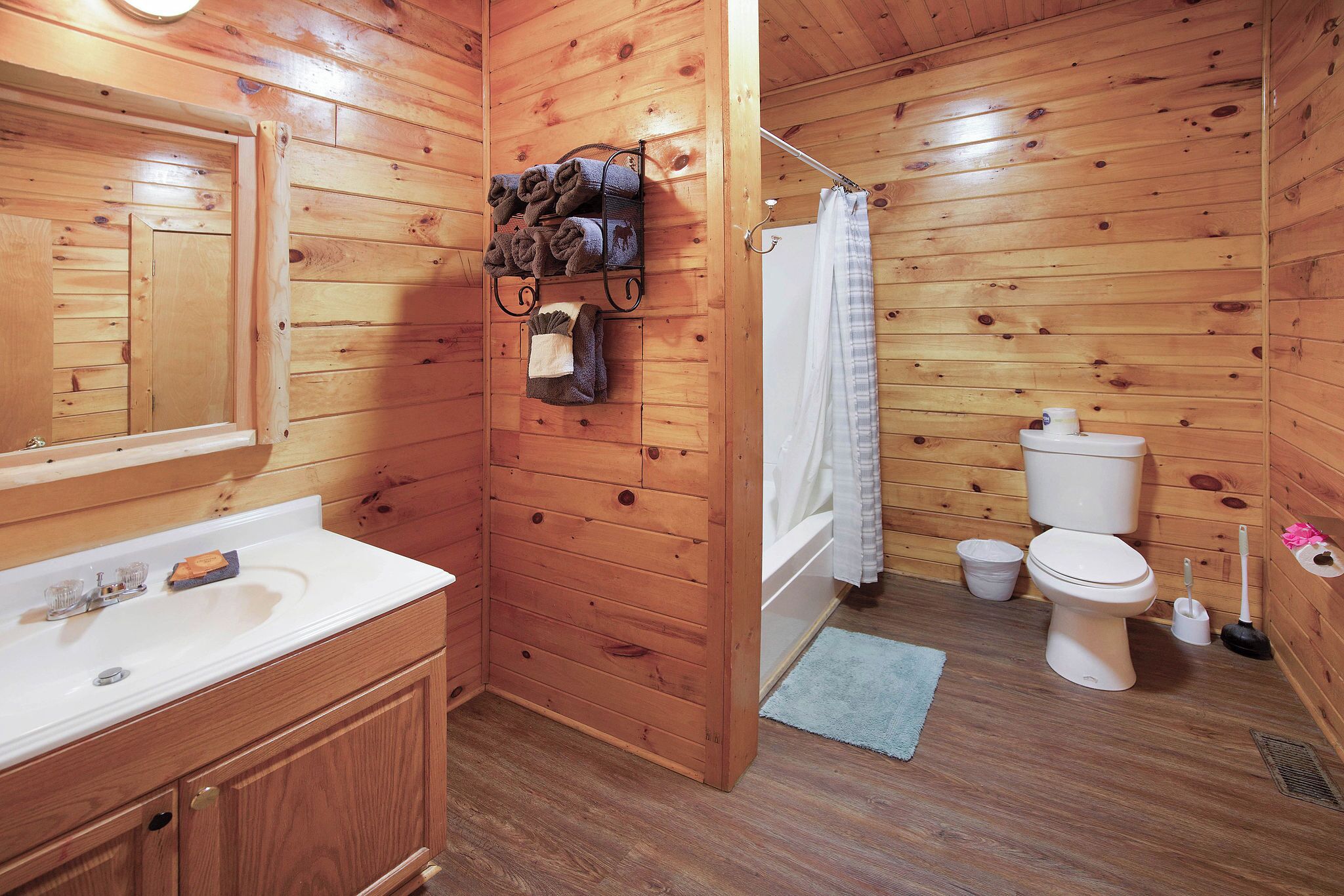 A wooden cabin bathroom with a sink, toilet, and shower.