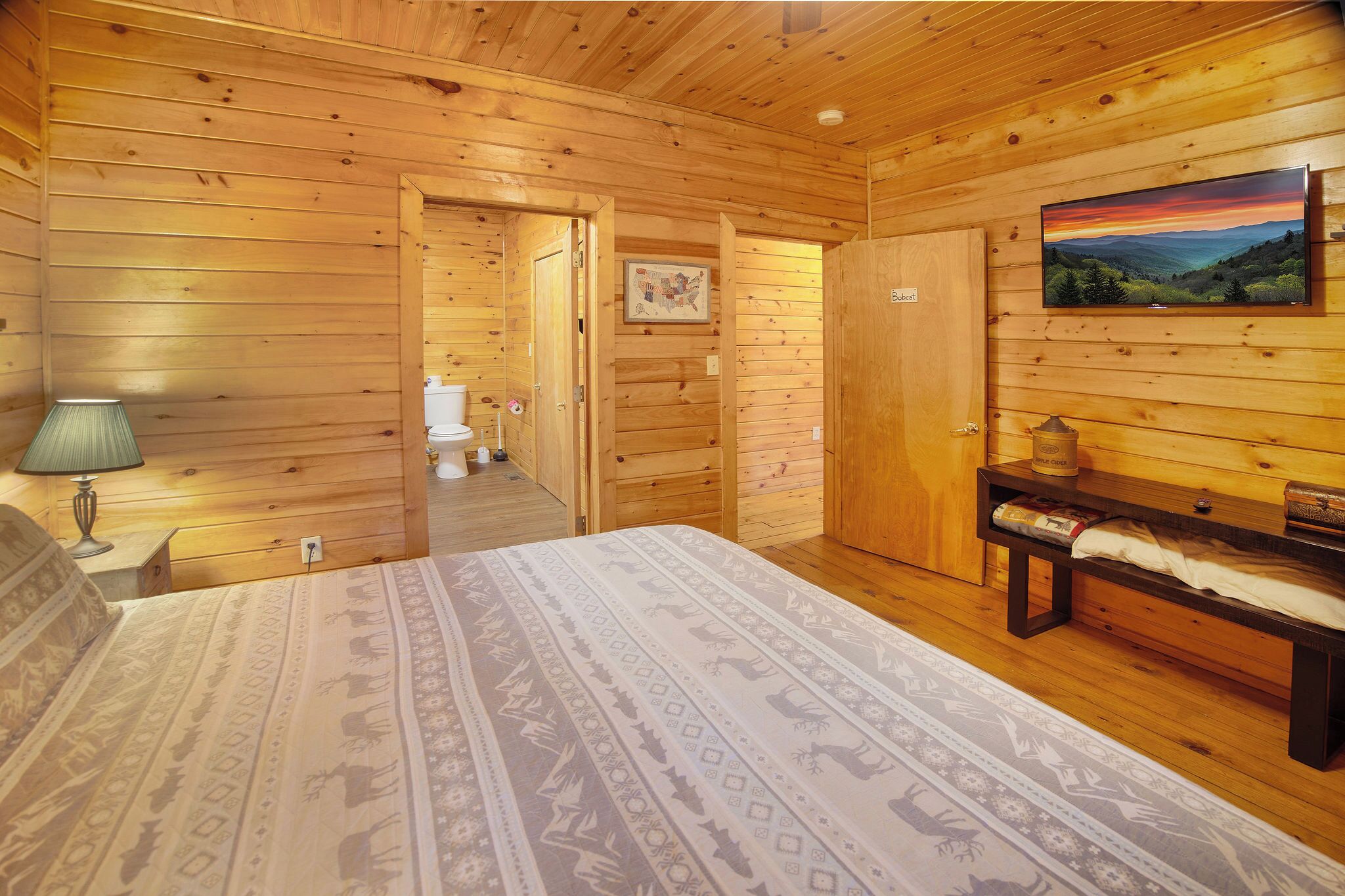 Ein Zimmer in einer Holzhütte mit einem Bett, einer Bank, einem Gemälde und einer Karte an der Wand.