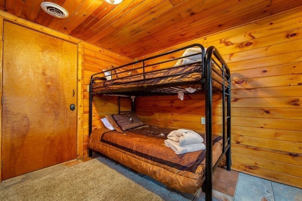 Une chambre avec des lits superposés, des murs en bois et un sol recouvert de moquette.