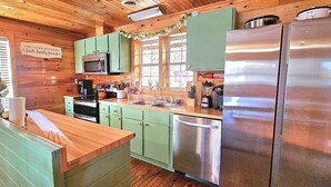 A kitchen with wooden cabinets, a stainless steel refrigerator, and a microwave. -  Smoky Mtn Hideaway - 7BR, Hot Tub +Movie Theatre + Darts+ Firepit+ Pets ok (Sevierville)