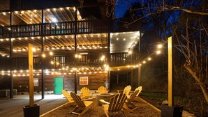 A wooden cabin with a deck, outdoor seating, and string lights. -  Smoky Mtn Hideaway - 7BR, Hot Tub +Movie Theatre + Darts+ Firepit+ Pets ok (Sevierville)