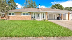A single-story house with a covered garage, a front porch with two chairs, and a well-maintained lawn. - New Remodel Modern Decor 2 Minutes to Restaurants Mall of LA Target I-10 TopGolf (Baton Rouge)