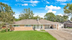 A single-story house with a covered porch, a small attached garage, and a well-maintained lawn. - New Remodel Modern Decor 2 Minutes to Restaurants Mall of LA Target I-10 TopGolf (Baton Rouge)