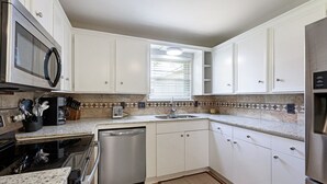 A kitchen with white cabinets, a microwave, a dishwasher, and a granite countertop. - New Remodel Modern Decor 2 Minutes to Restaurants Mall of LA Target I-10 TopGolf (Baton Rouge)