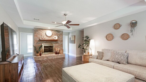A spacious living room with a fireplace, a ceiling fan, and a large window. - New Remodel Modern Decor 2 Minutes to Restaurants Mall of LA Target I-10 TopGolf (Baton Rouge)