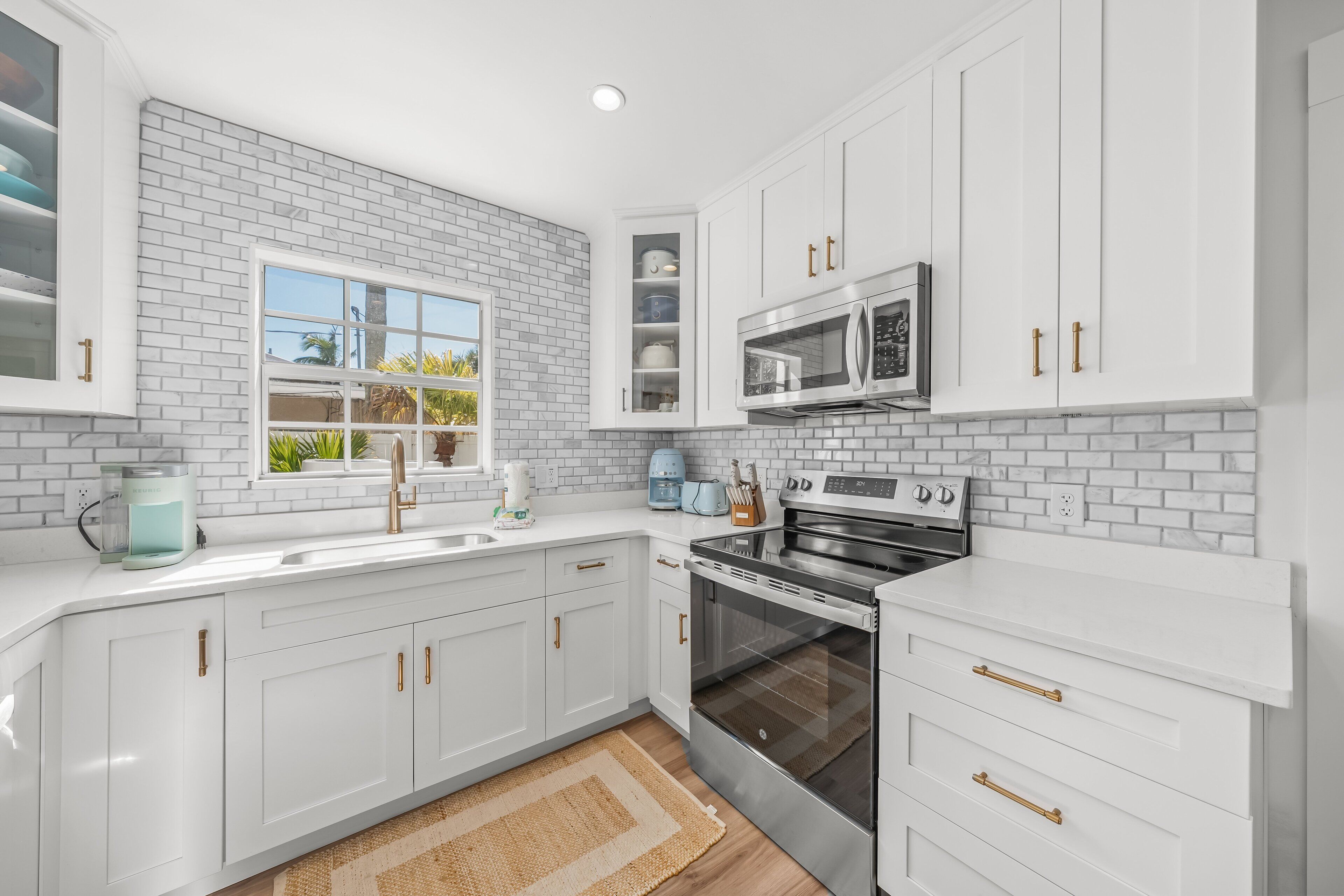 A modern kitchen with white cabinets, a stainless steel oven, and a microwave.