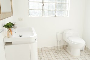 A bathroom with a white sink, toilet, and a window with frosted glass. - Aparta Hotel Tocancipa (Tocancipá)