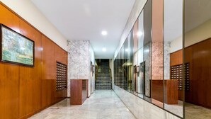 A modern hallway with marble flooring, wooden paneling, and a large mirror reflecting the interior. - Holi-Rent Martín Villa (Sevilla)