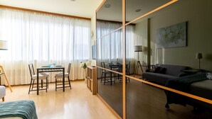 A modern hotel room with a dining area, a sofa, and a large mirror. - Holi-Rent Martín Villa (Sevilla)