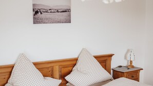 A bed with a wooden headboard, checkered bedding, a bedside table with a lamp, and a wall-mounted picture.