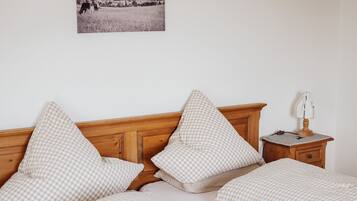 Un lit avec une tête de lit en bois, une literie à carreaux, une table de chevet avec une lampe et un tableau accroché au mur.