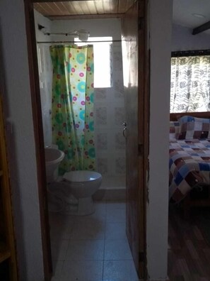 A small bathroom with a toilet, a sink, and a shower area. - Las Cabañas Mongui (Monguí)