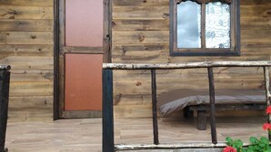 Una cabaña de madera con una ventana, una puerta y un banco en su interior.