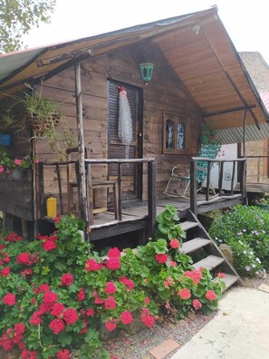 A rustic wooden cabin with a porch, a small staircase, and a garden with red flowers. - Las Cabañas Mongui (Monguí)