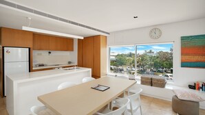 A modern kitchen with white cabinetry, a built-in fridge, and a large window offering a view of the city.