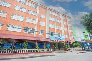 Un edificio de varios pisos con fachada roja, toldo azul y un letrero que dice 'Sorrento Beach'.