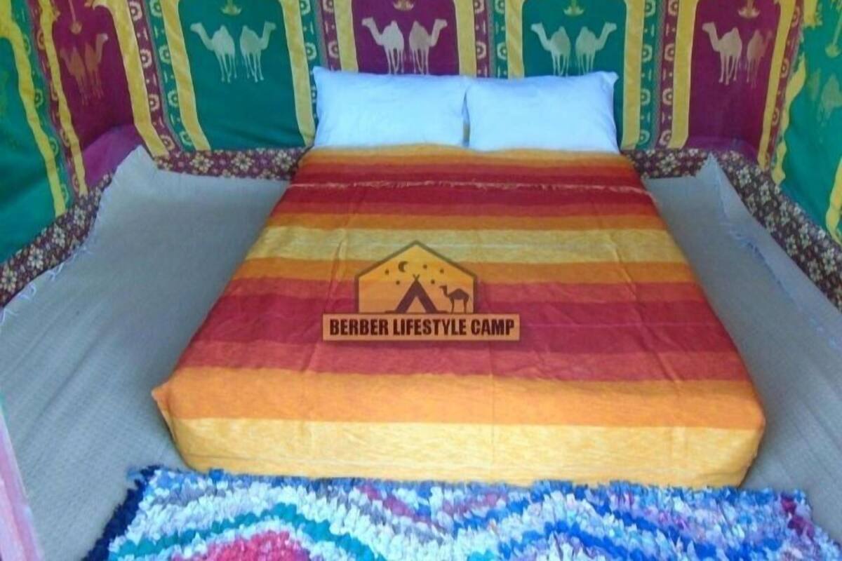 A bed with a colorful striped blanket and a headboard with camel designs.