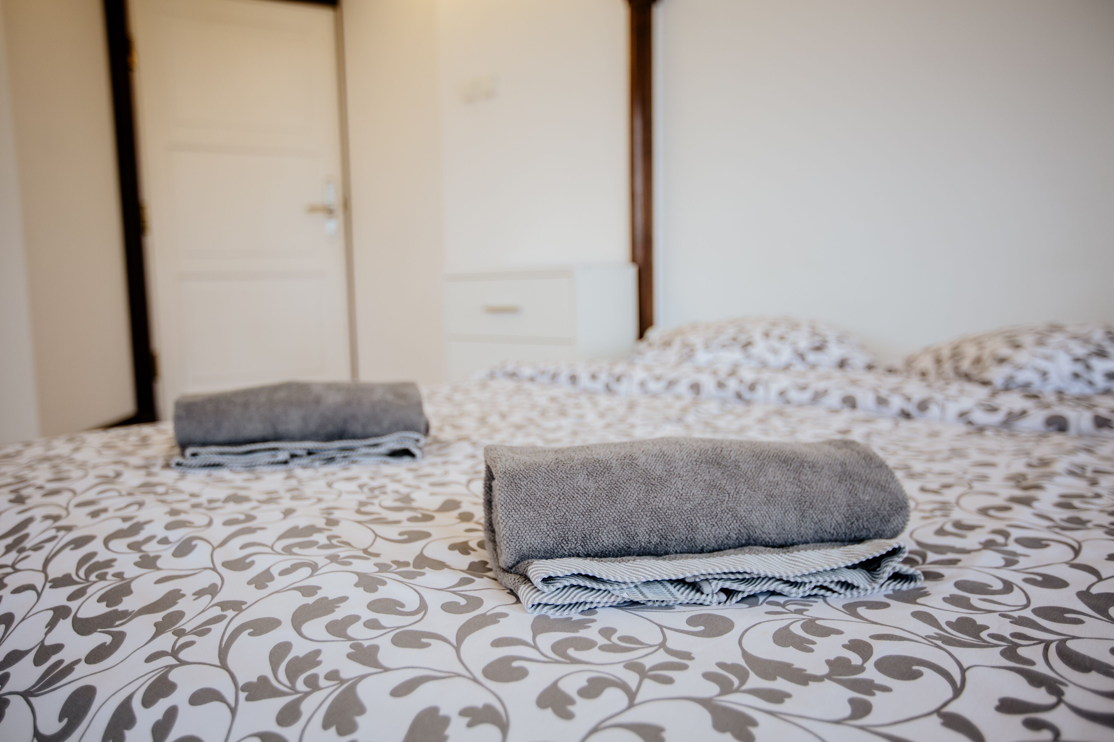 A neatly made bed with patterned bedding and folded towels.