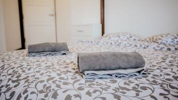 A neatly made bed with patterned bedding and folded towels.