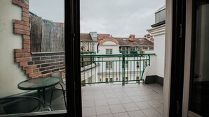 Un balcón con vista a un patio, una pared de ladrillo y una mesa con sillas.