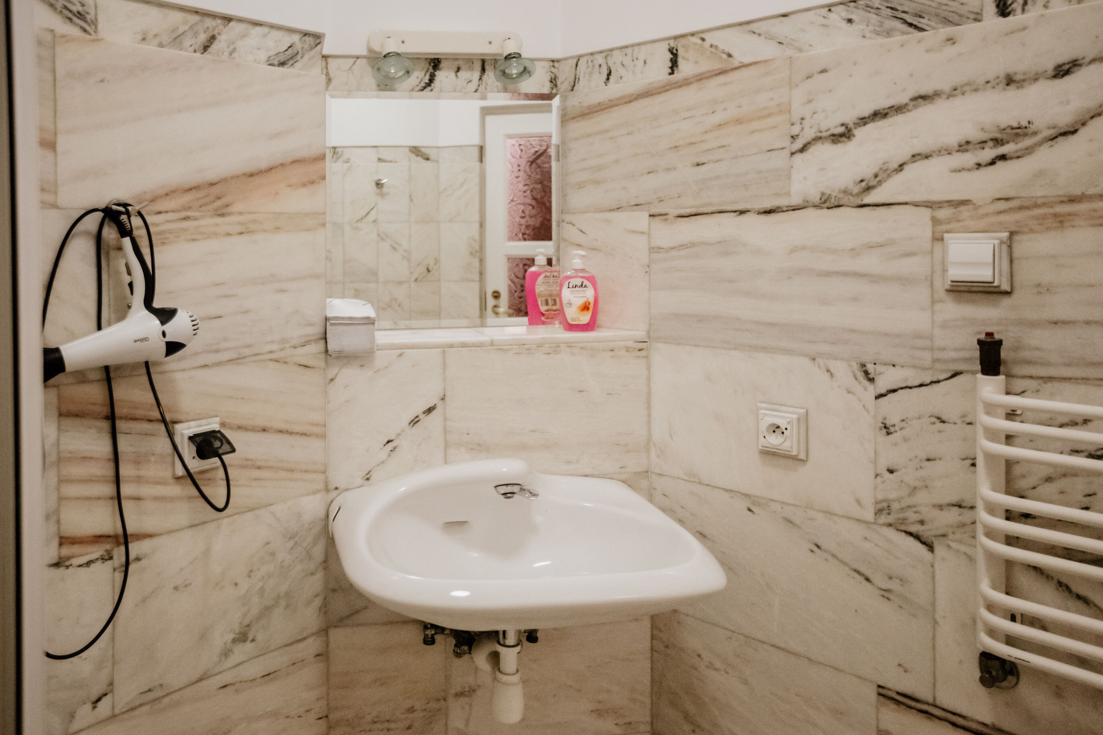 A bathroom with a marble sink, a hairdryer, and a mirror.