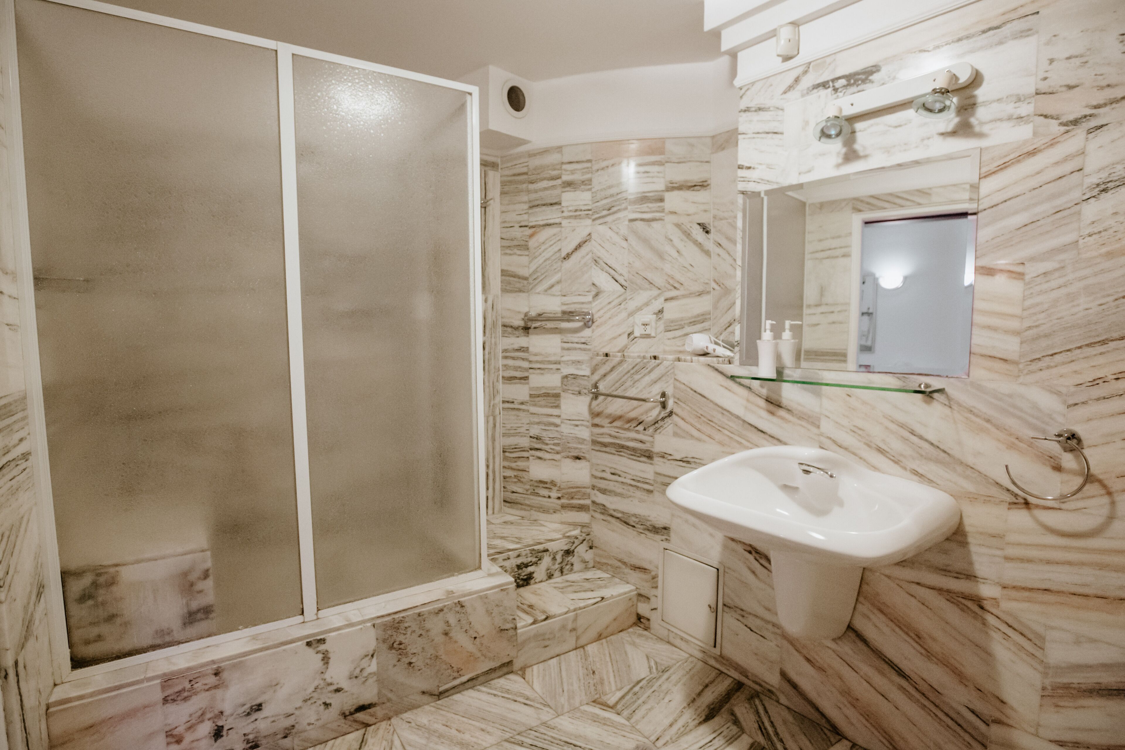 Un baño con ducha, lavabo y espejo.