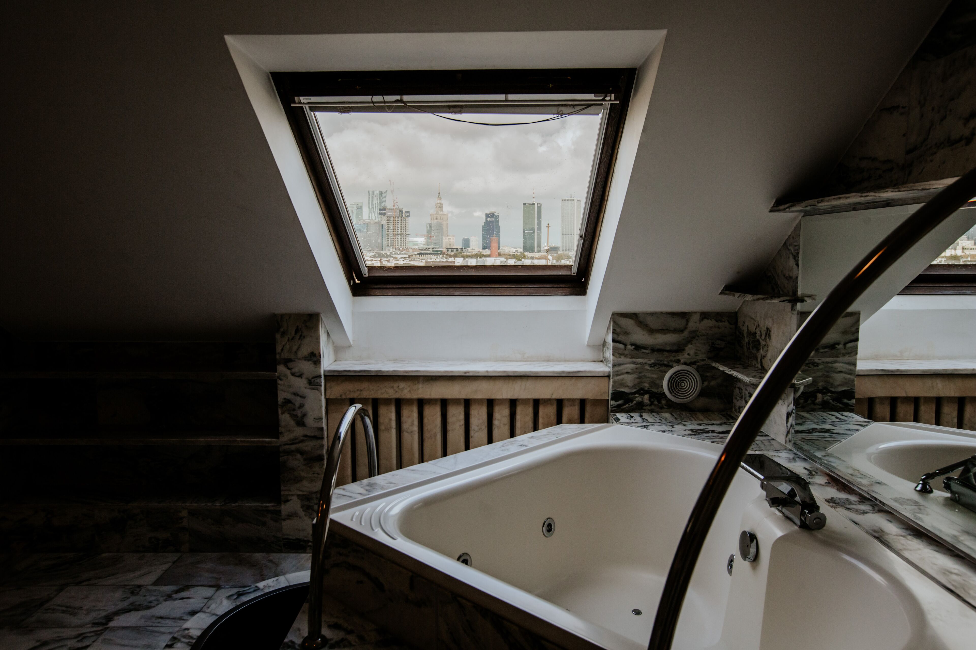 A modern bathroom with a skylight, a bathtub, and a shower area.