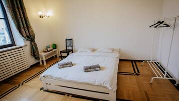 A neatly arranged bedroom with a bed, bedside table, chair, and a clothing rack.